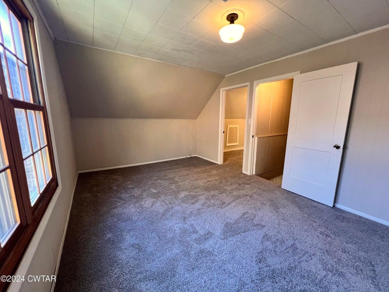 Bonus room featuring dark carpet and vaulted ceiling