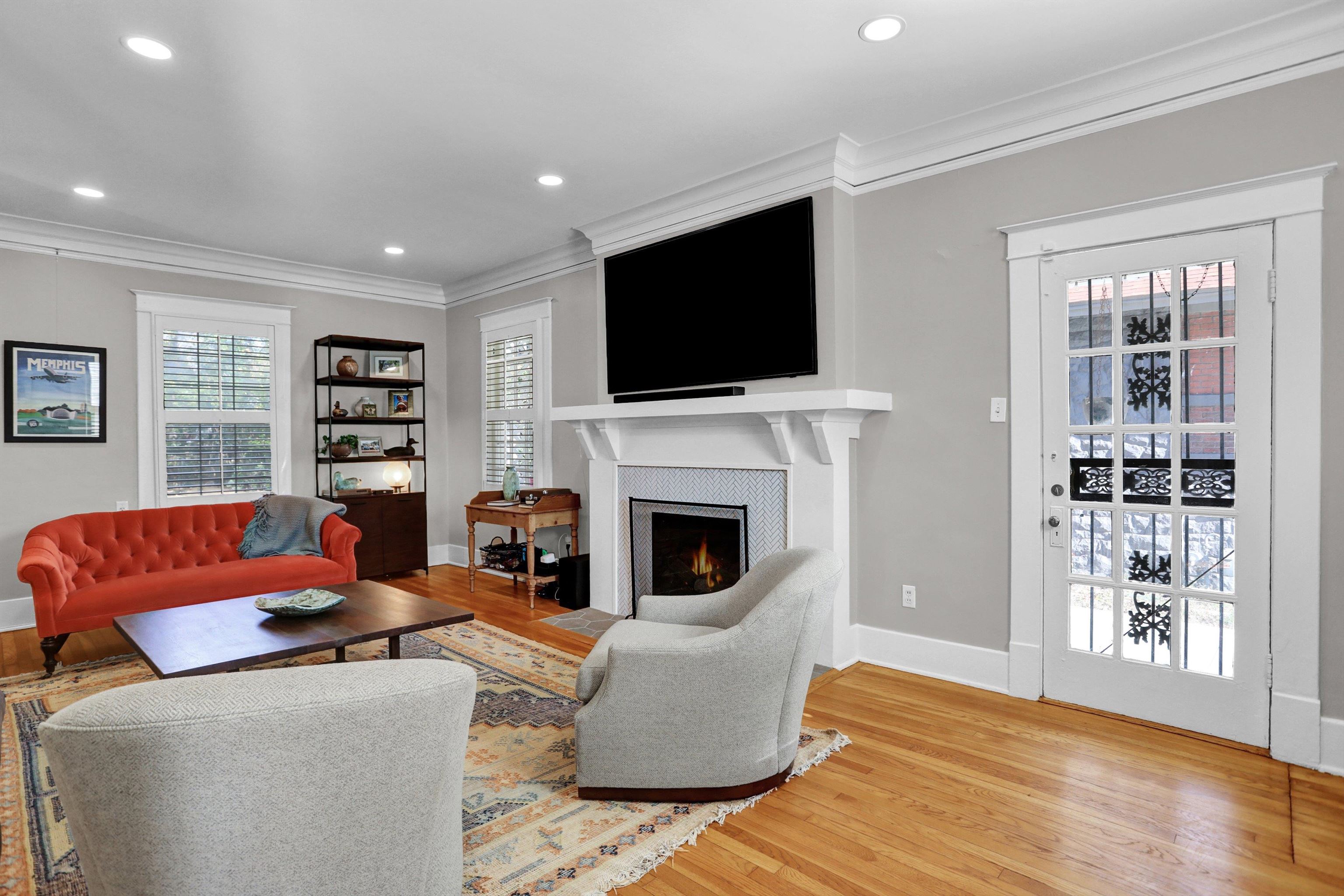 Living room featuring hardwood / wood-style floors, crown molding, and a tiled fireplace