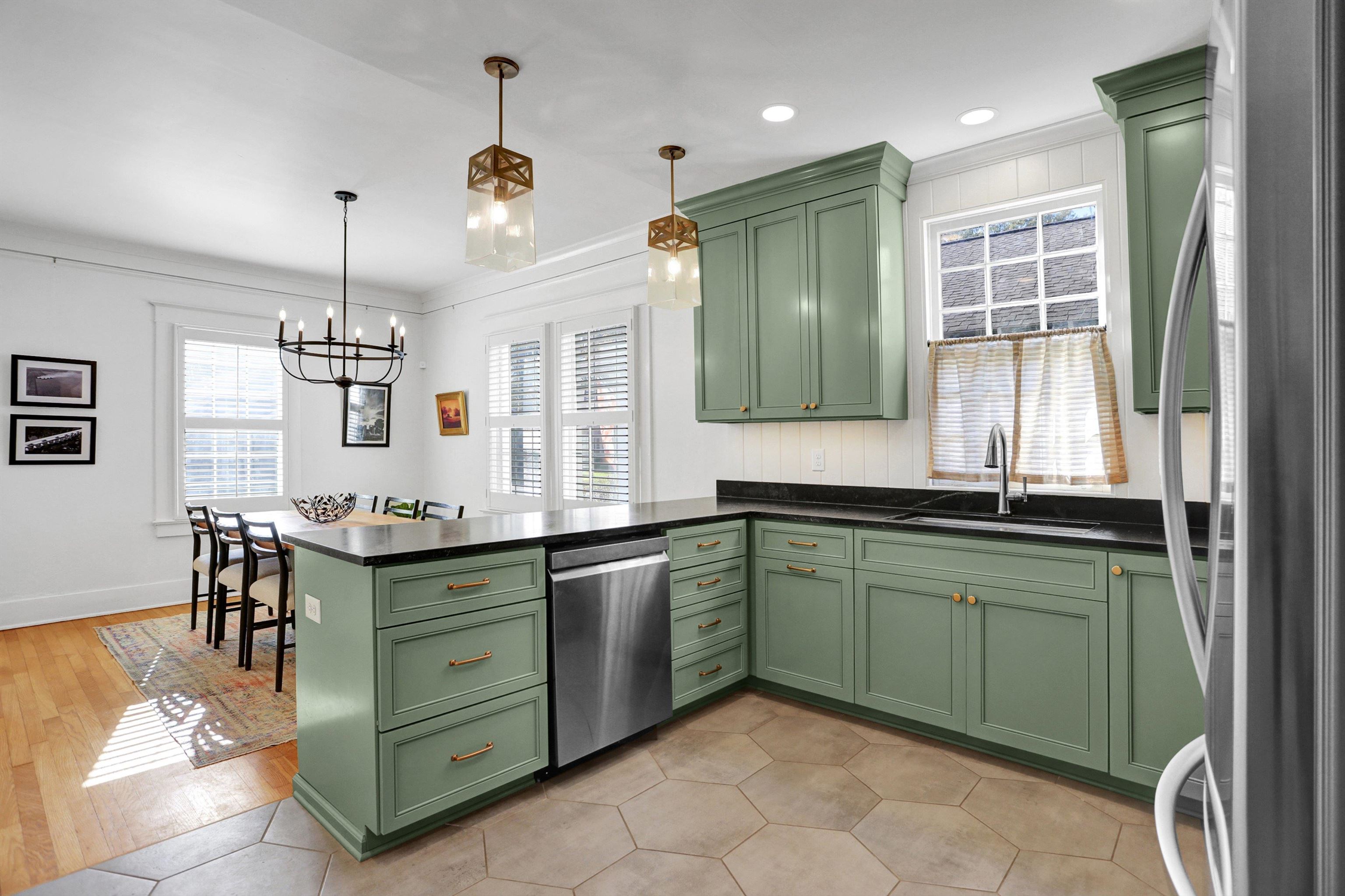 Kitchen with kitchen peninsula, appliances with stainless steel finishes, pendant lighting, light hardwood / wood-style flooring, and green cabinets