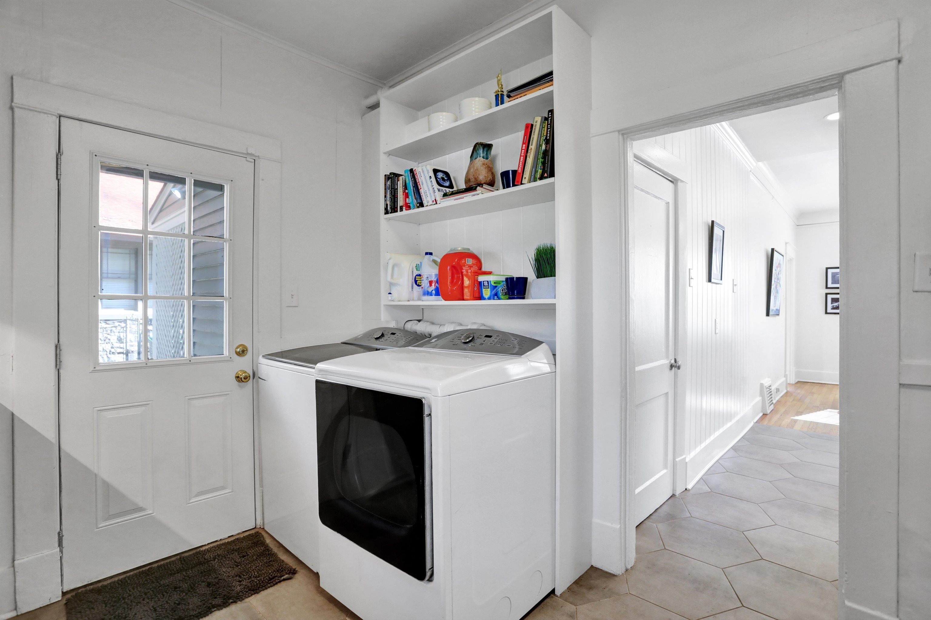 Laundry area with light tile patterned floors, washing machine and dryer, and crown molding
