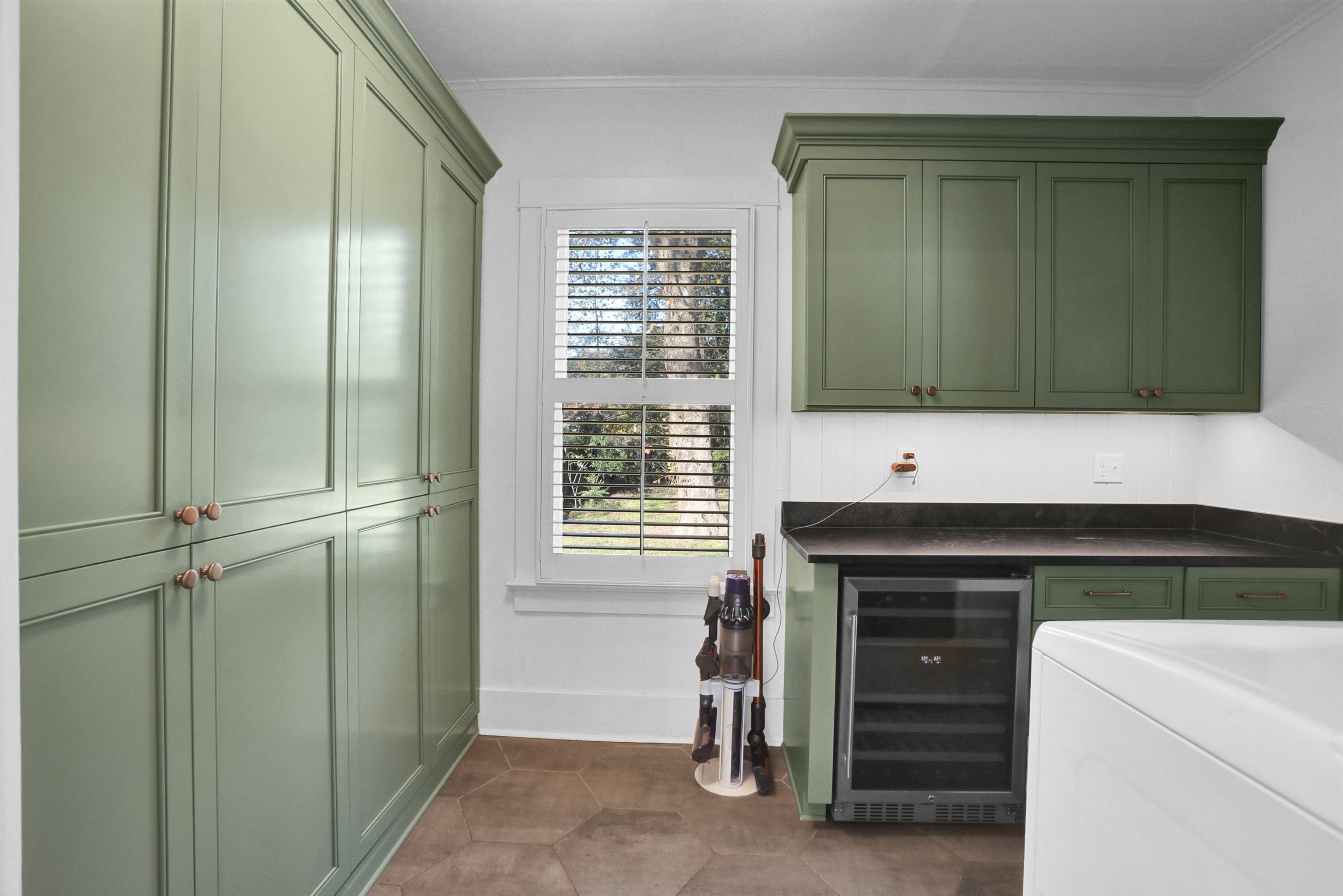 Bar with dark tile patterned flooring, wine cooler, green cabinets, and crown molding