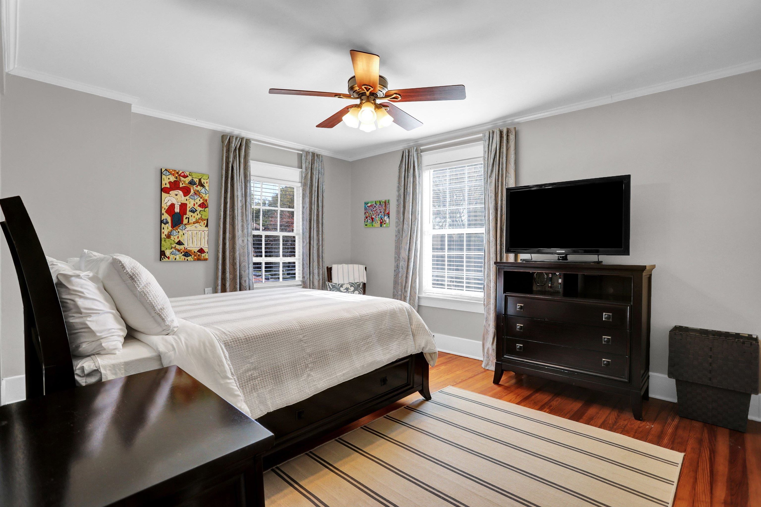 Bedroom with wood-type flooring, multiple windows, ornamental molding, and ceiling fan
