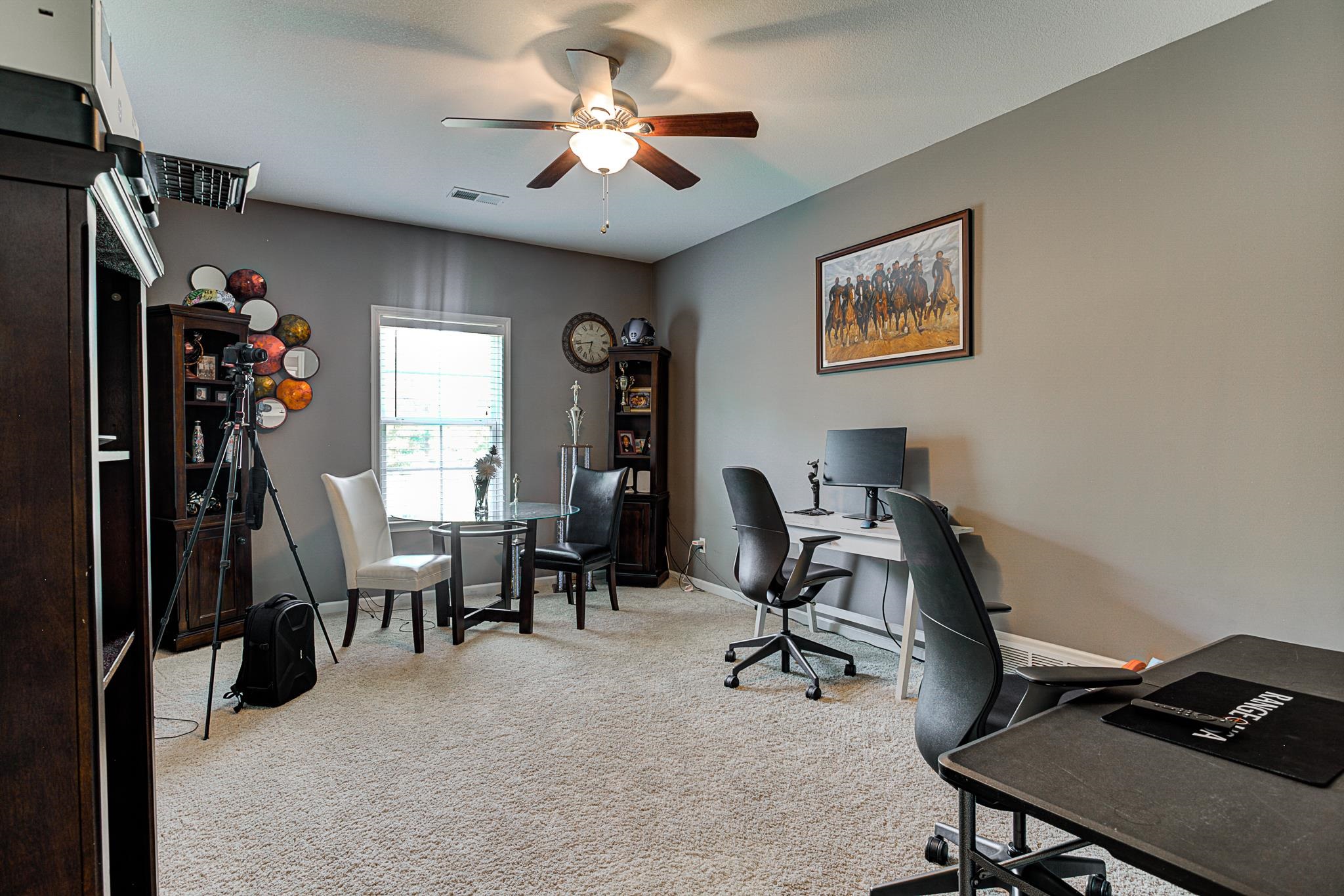 Office with light carpet and ceiling fan