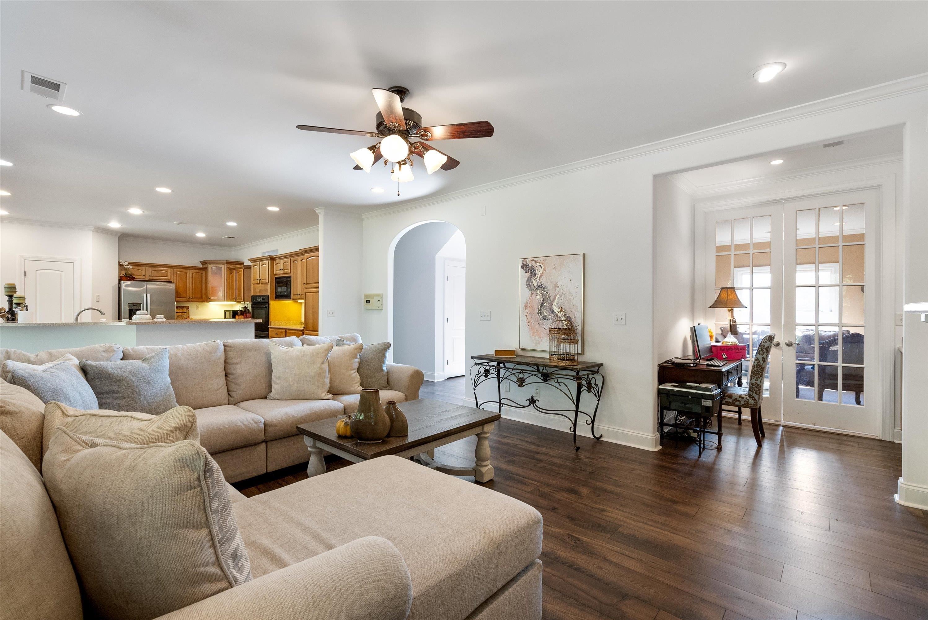 Living room featuring ceiling fan, ornamental molding, and dark wood-type flooring