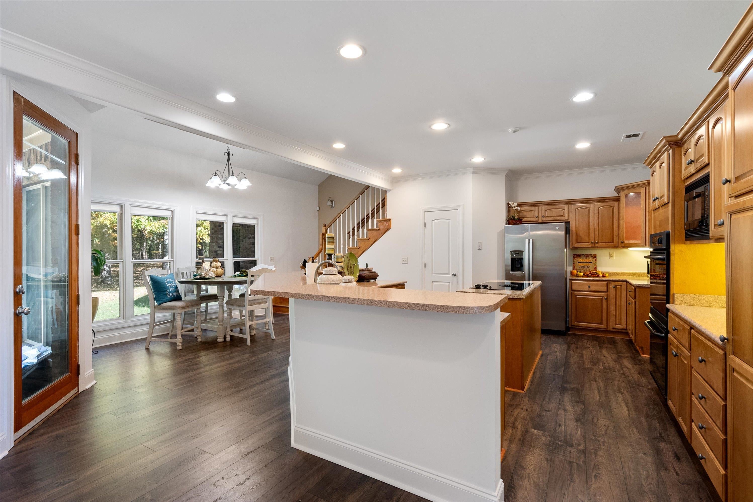 Kitchen featuring black appliances, pendant lighting, dark hardwood / wood-style flooring, and an island with sink