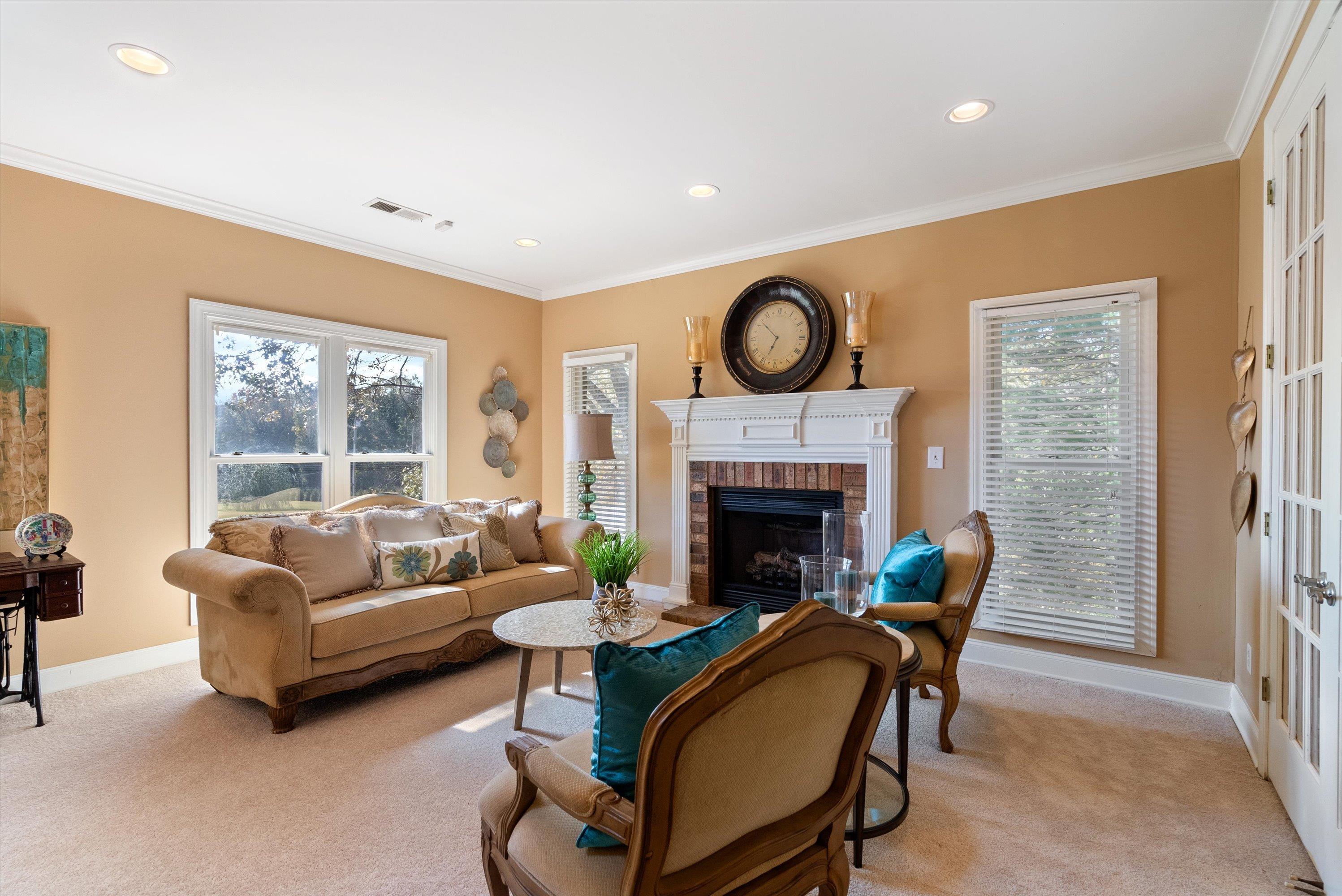 Living room featuring a fireplace, french doors, light colored carpet, and ornamental molding