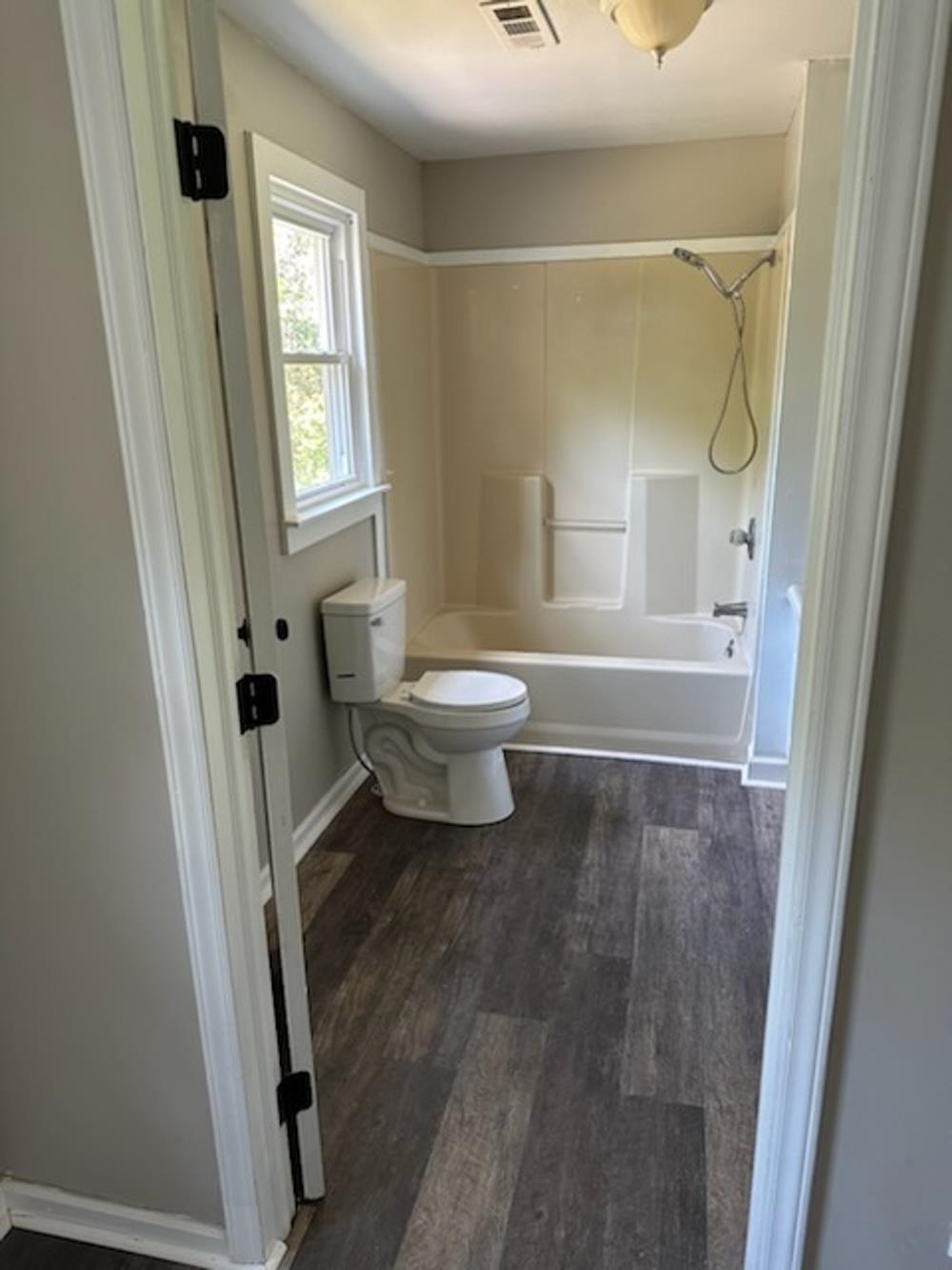 Bathroom with hardwood / wood-style floors, toilet, and tub / shower combination