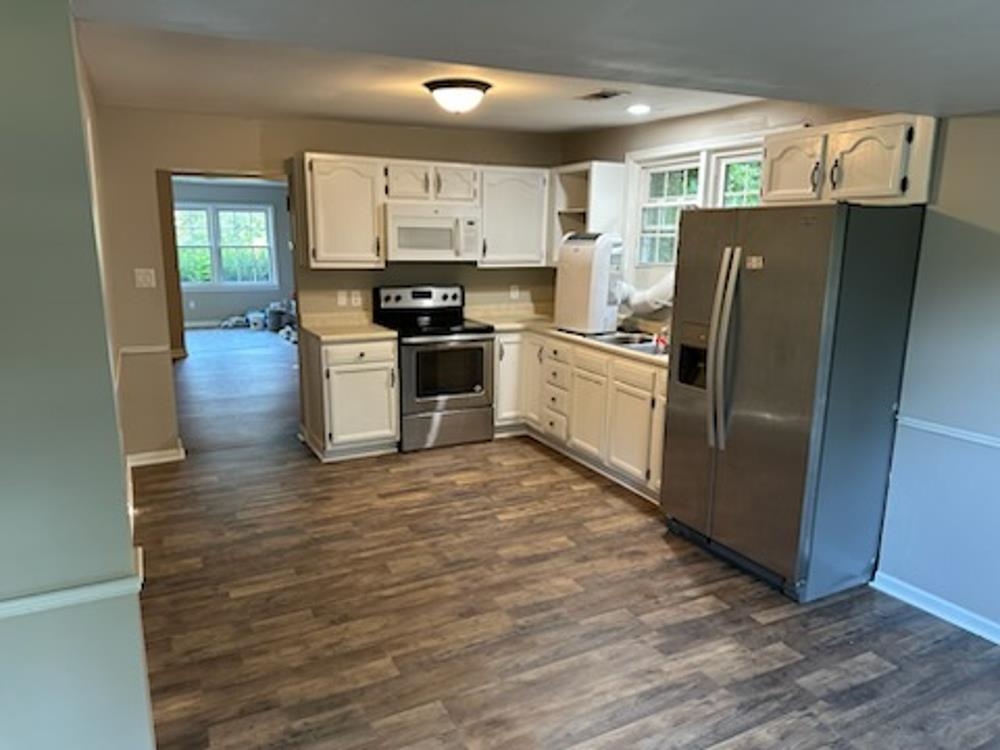 Kitchen with white cabinets, dark wood-type flooring, and appliances with stainless steel finishes