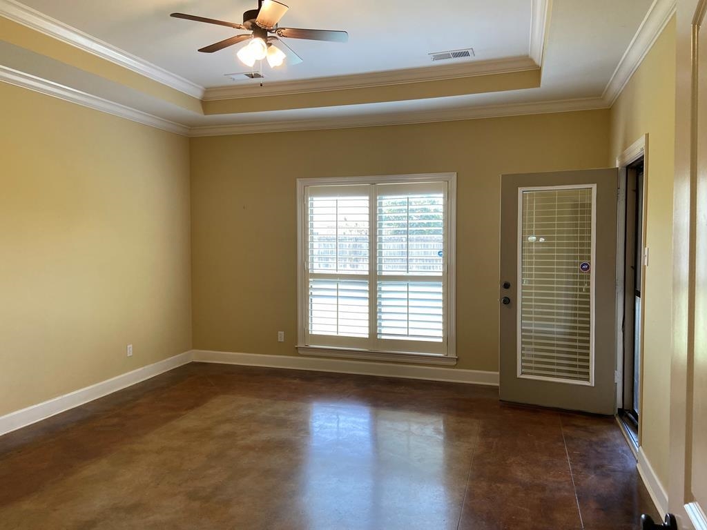Empty room featuring a tray ceiling, crown molding, and ceiling fan
