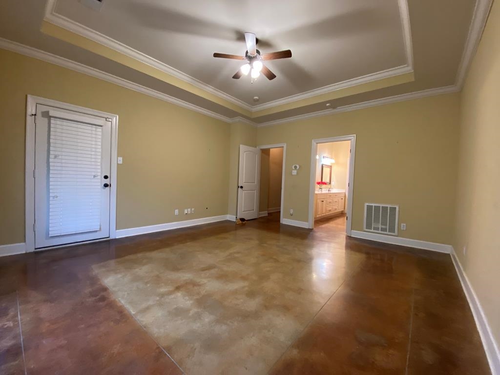 Spare room featuring ceiling fan, a raised ceiling, and ornamental molding
