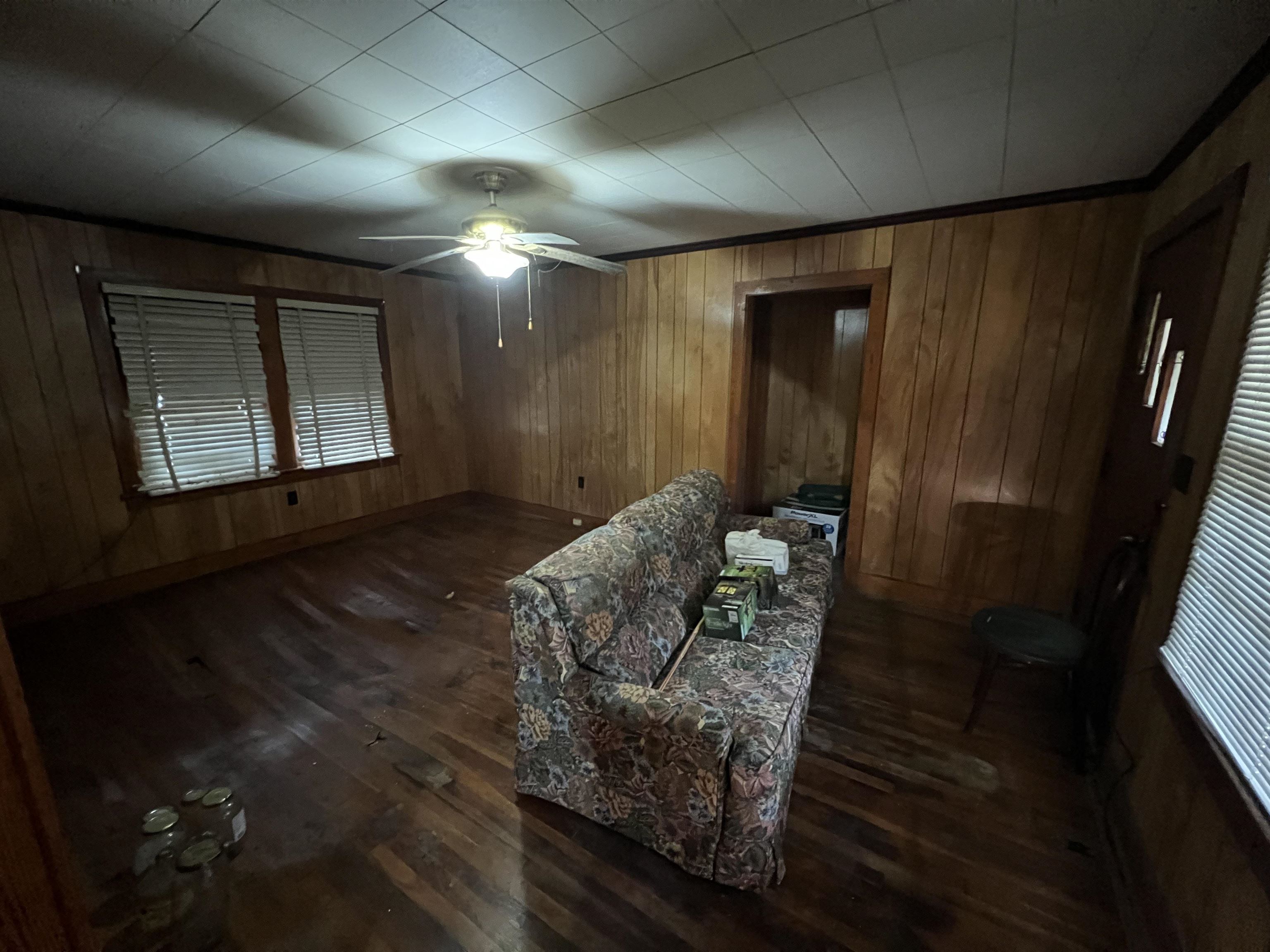 Interior space featuring ceiling fan, dark wood-type flooring, and wood walls