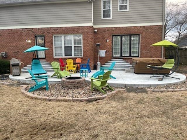 Back of house featuring a patio, a hot tub, and an outdoor fire pit