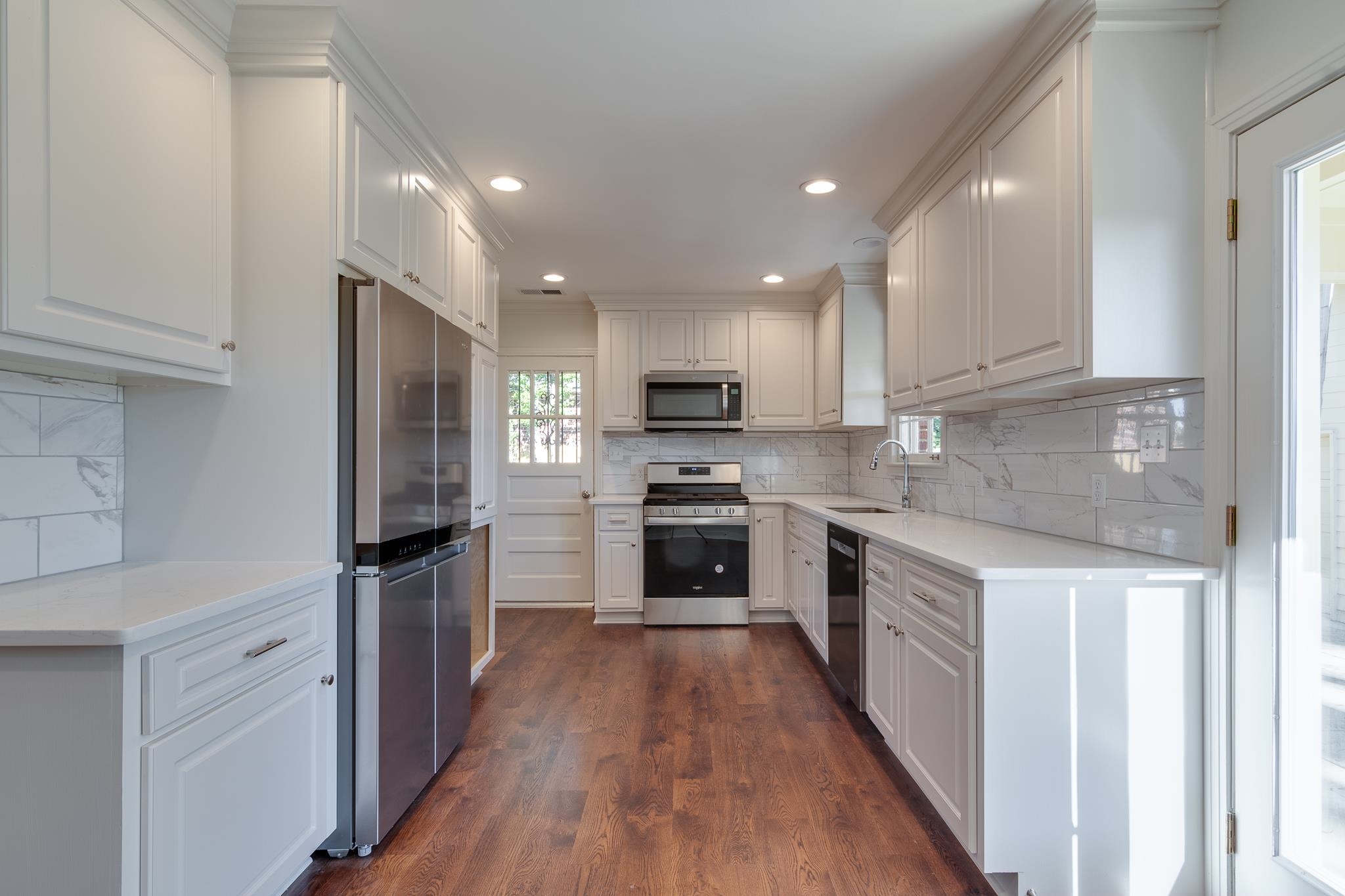 Kitchen with white cabinets, appliances with stainless steel finishes, dark wood-type flooring, and sink