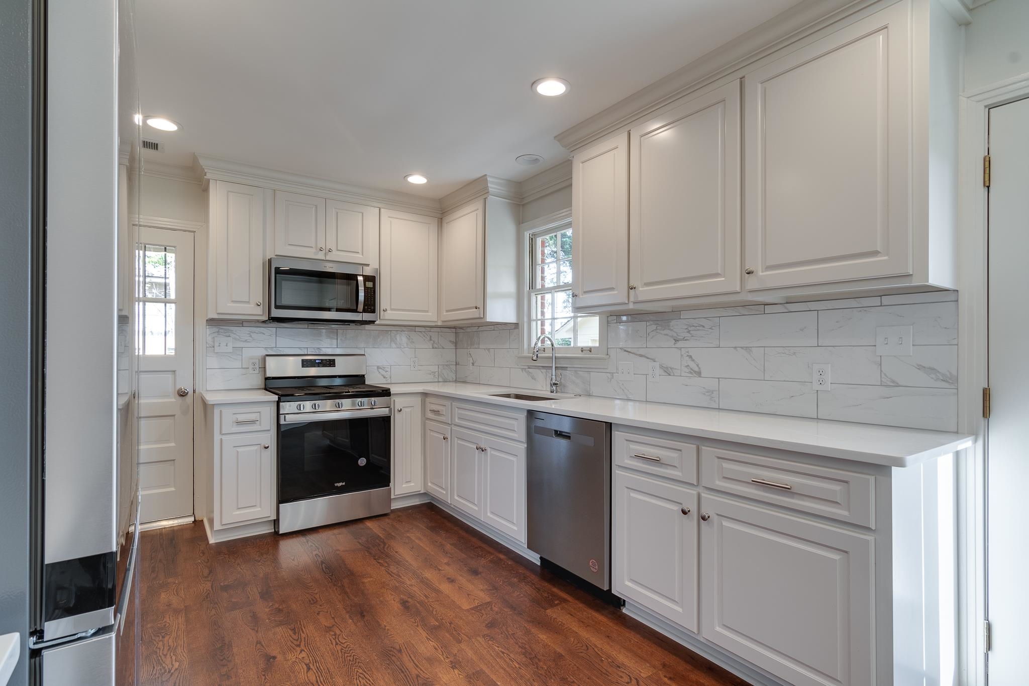 Kitchen featuring appliances with stainless steel finishes, dark hardwood / wood-style floors, white cabinetry, and sink