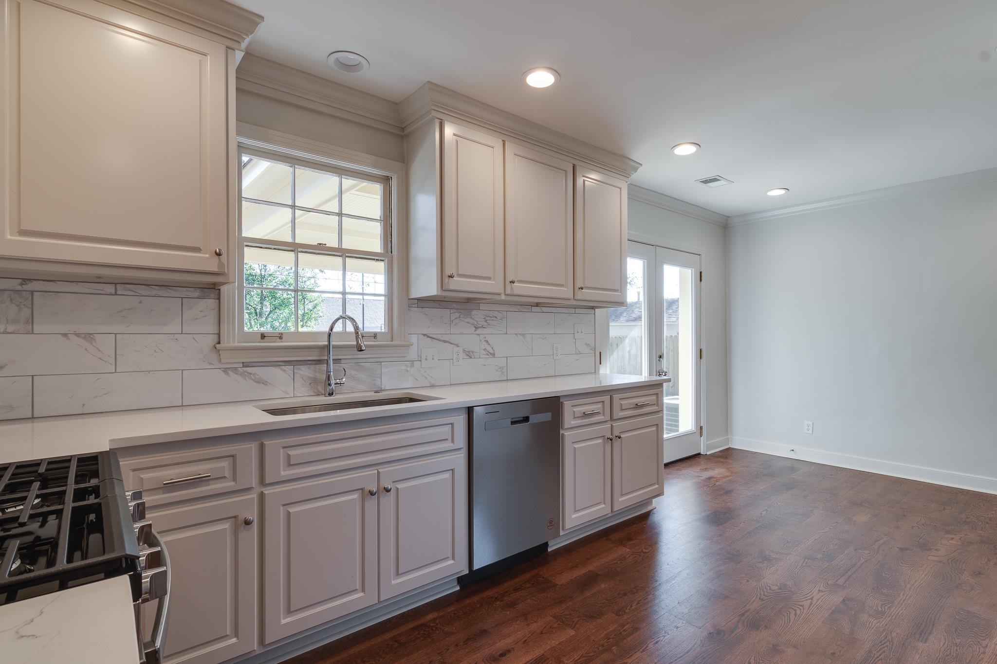 Kitchen with dishwasher, stove, sink, crown molding, and dark hardwood / wood-style flooring