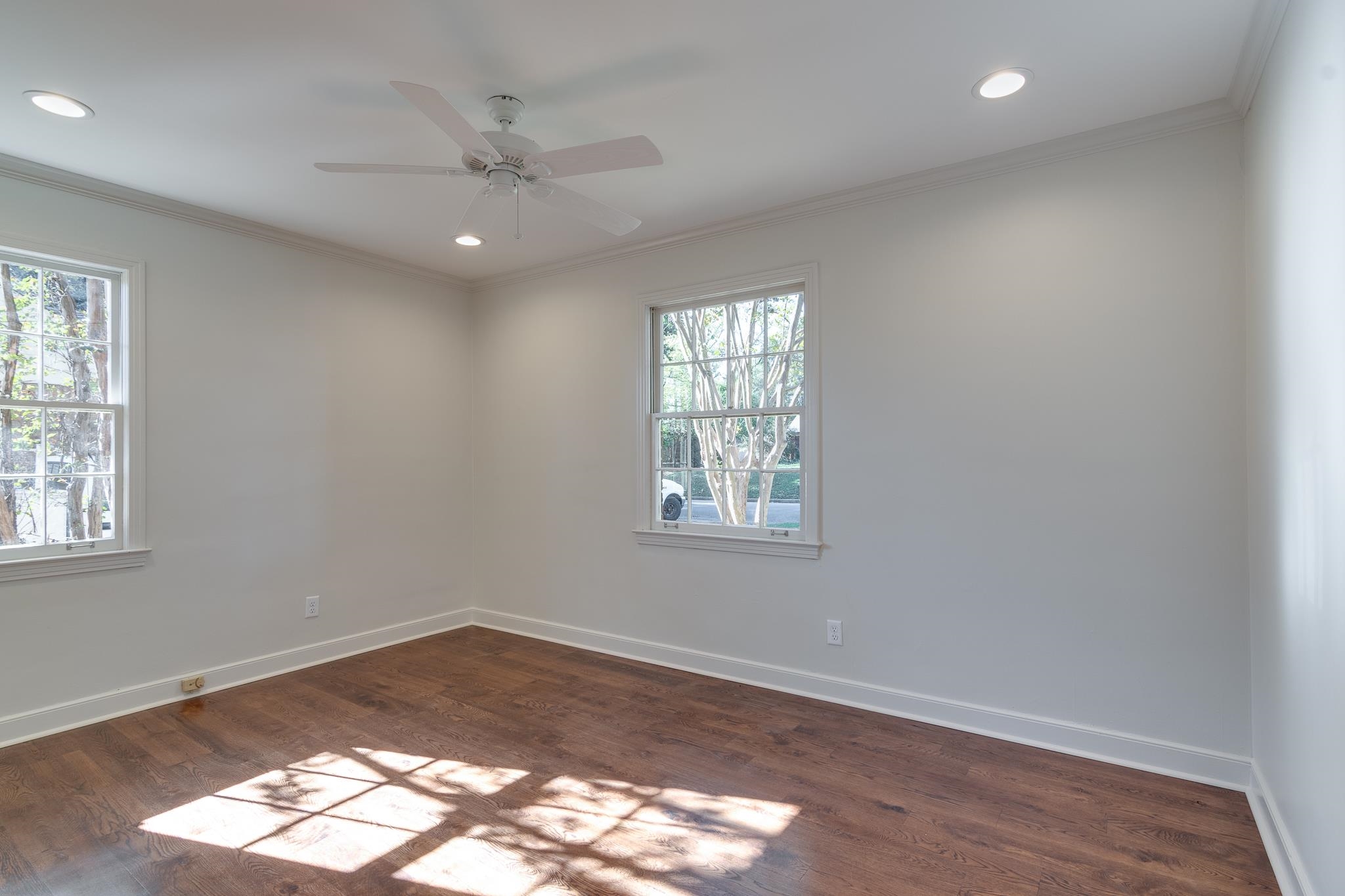 Empty room featuring dark hardwood / wood-style floors, crown molding, and a wealth of natural light