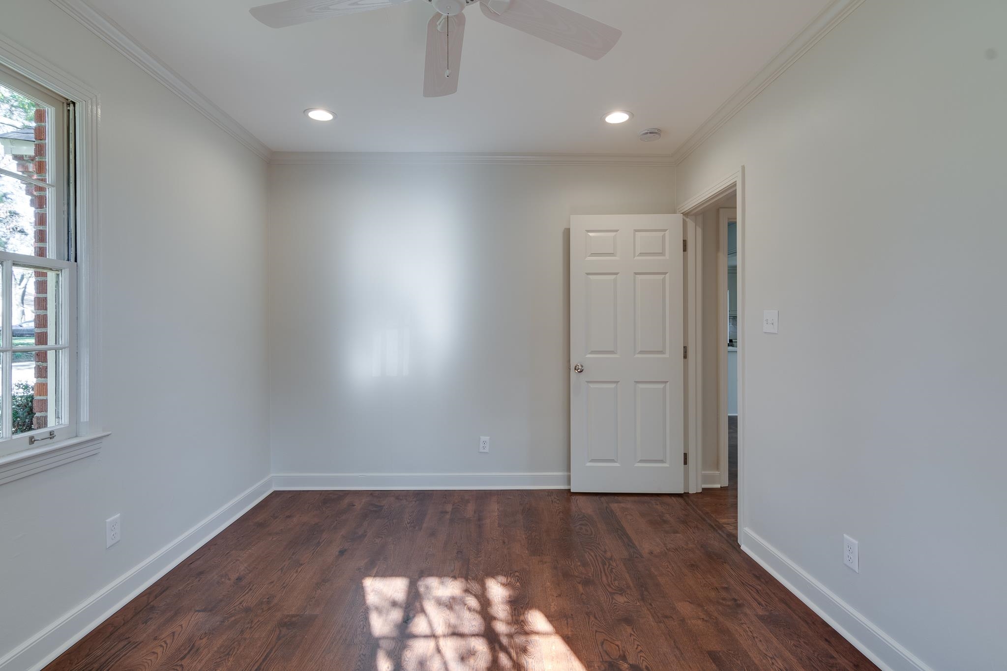 Empty room featuring ornamental molding, ceiling fan, and dark wood-type flooring