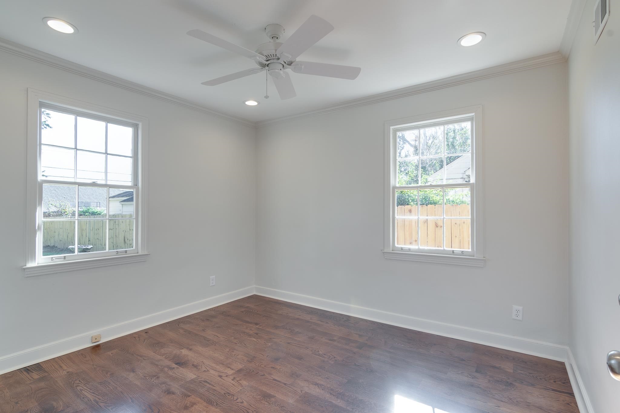 Unfurnished room featuring ceiling fan, dark wood-type flooring, and ornamental molding