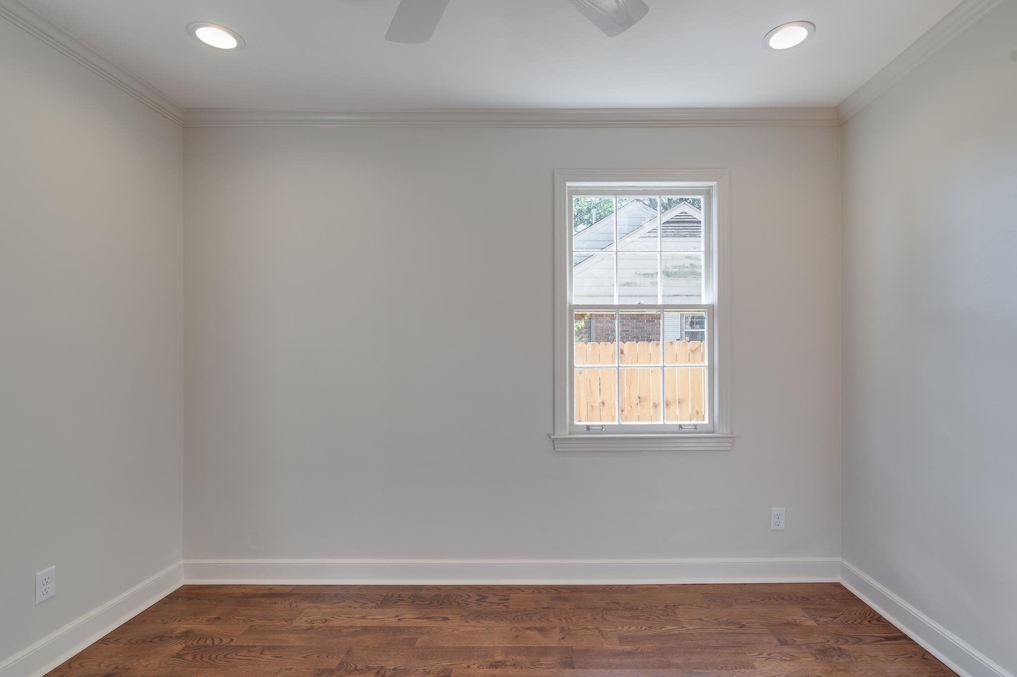 Unfurnished room featuring ceiling fan, dark wood-type flooring, and ornamental molding