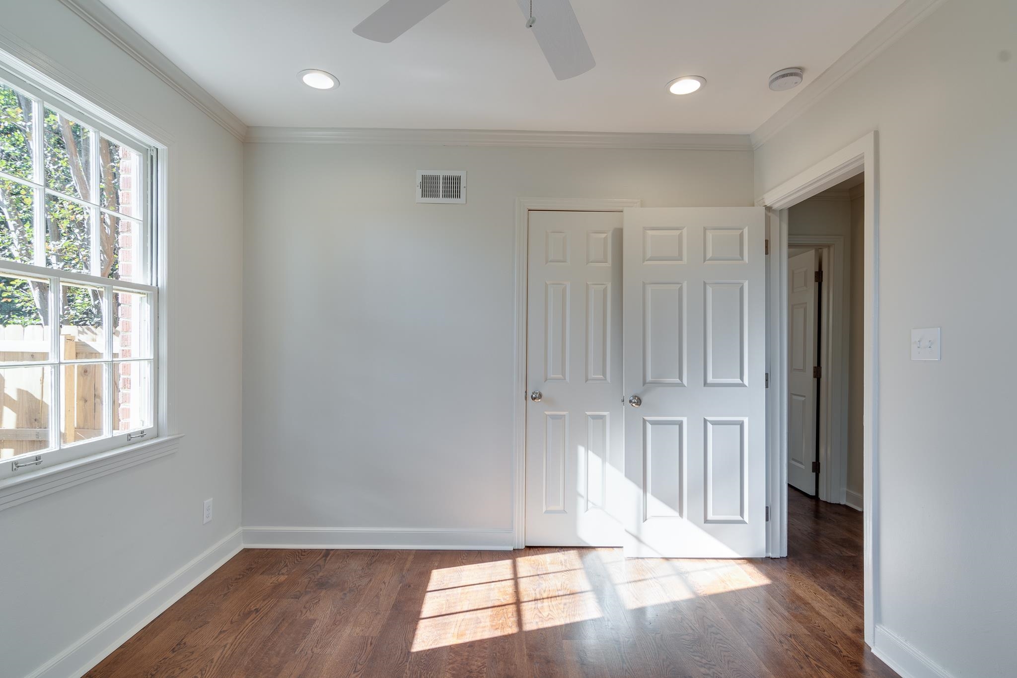 Unfurnished room featuring ceiling fan, crown molding, and dark wood-type flooring