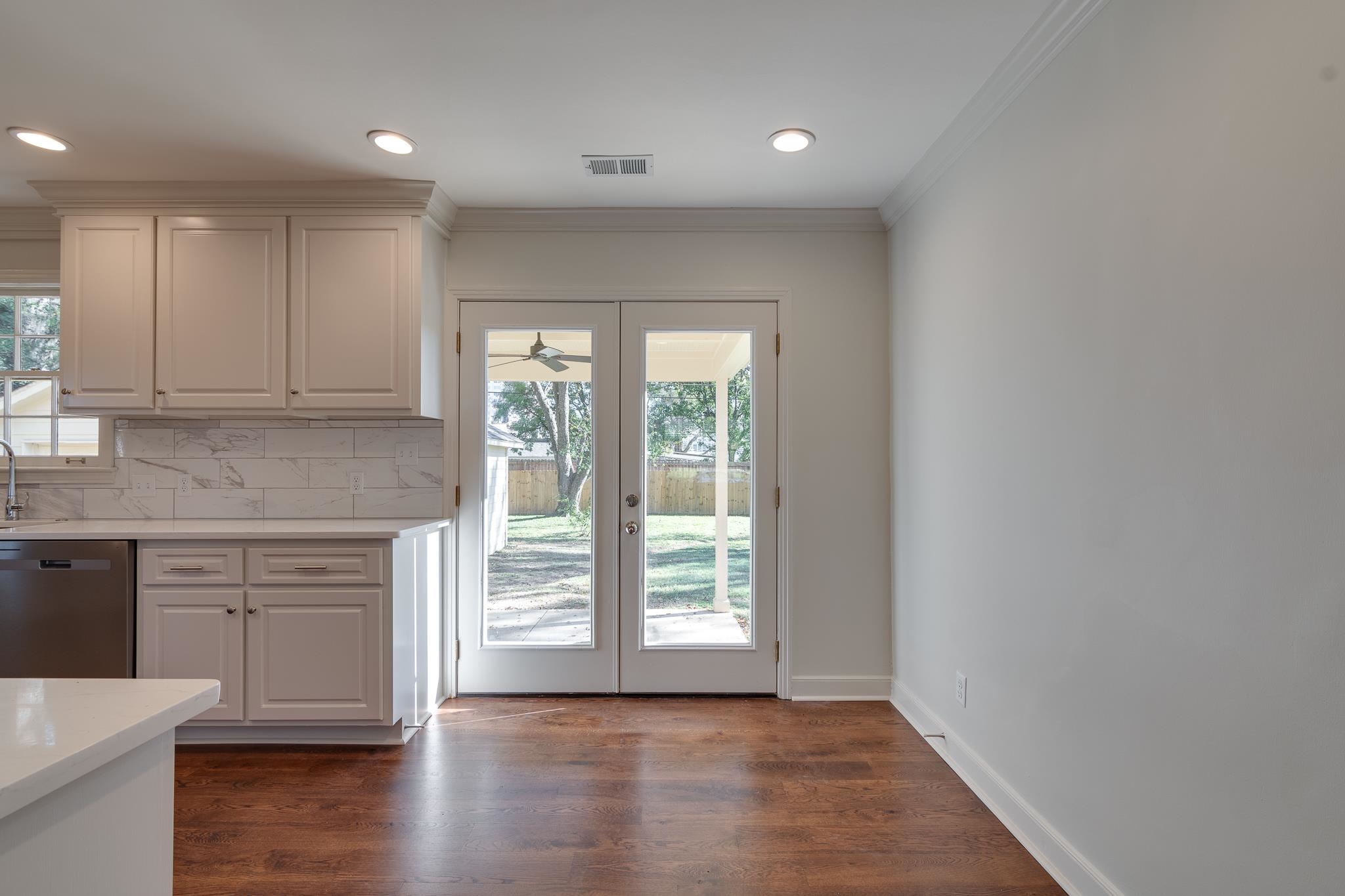 Kitchen with french doors, dark hardwood / wood-style floors, stainless steel dishwasher, and a healthy amount of sunlight