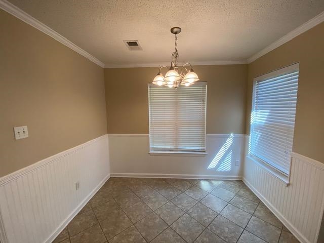 Unfurnished room with a textured ceiling, tile patterned floors, a notable chandelier, and ornamental molding