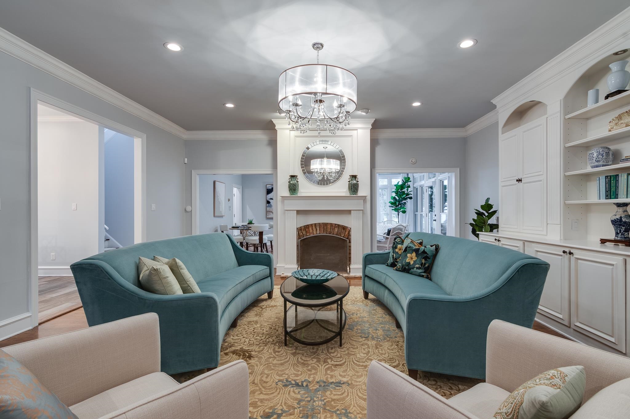 Living room with a fireplace, crown molding, hardwood flooring, and a notable chandelier