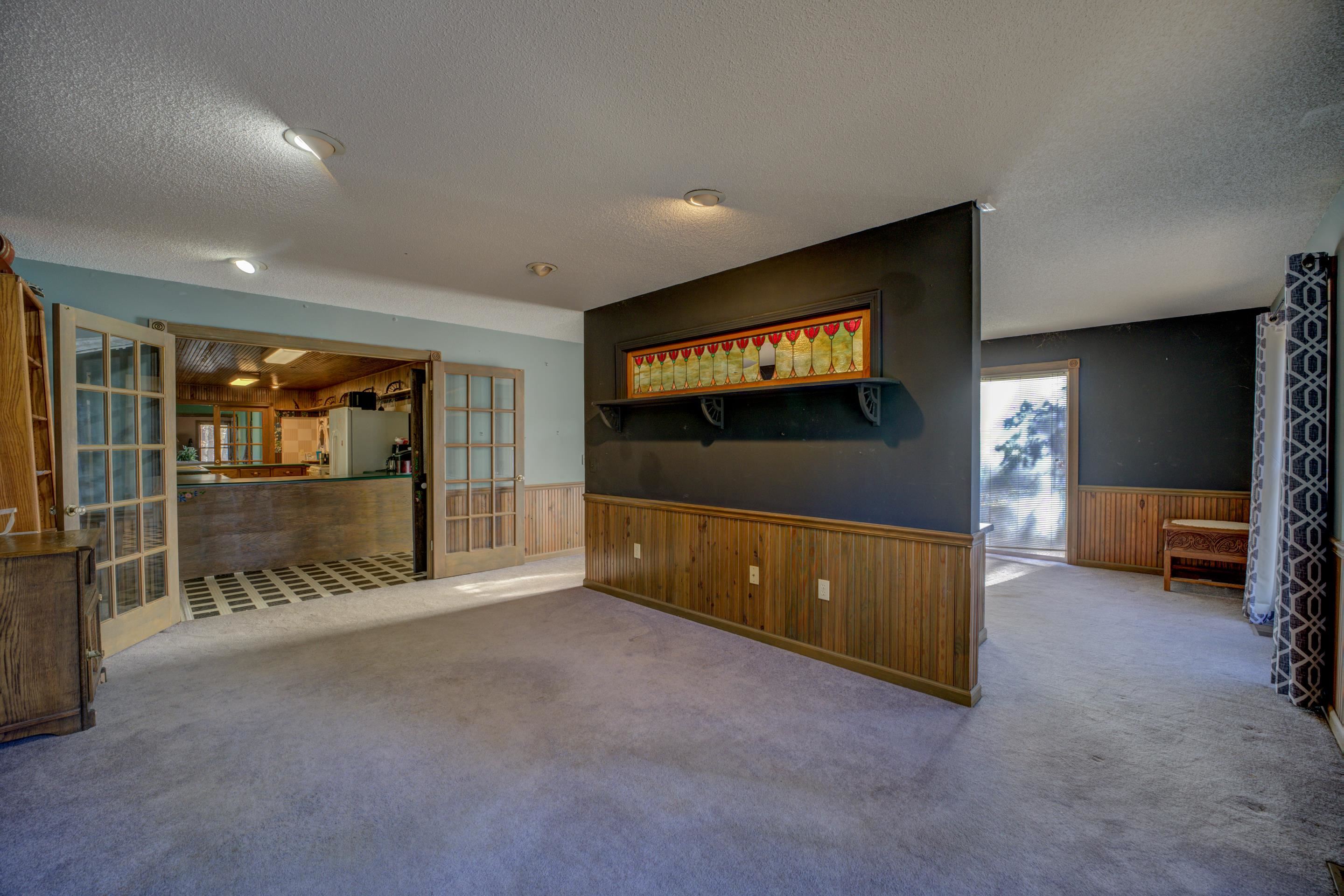 Unfurnished living room with wood walls, carpet floors, a textured ceiling, and french doors