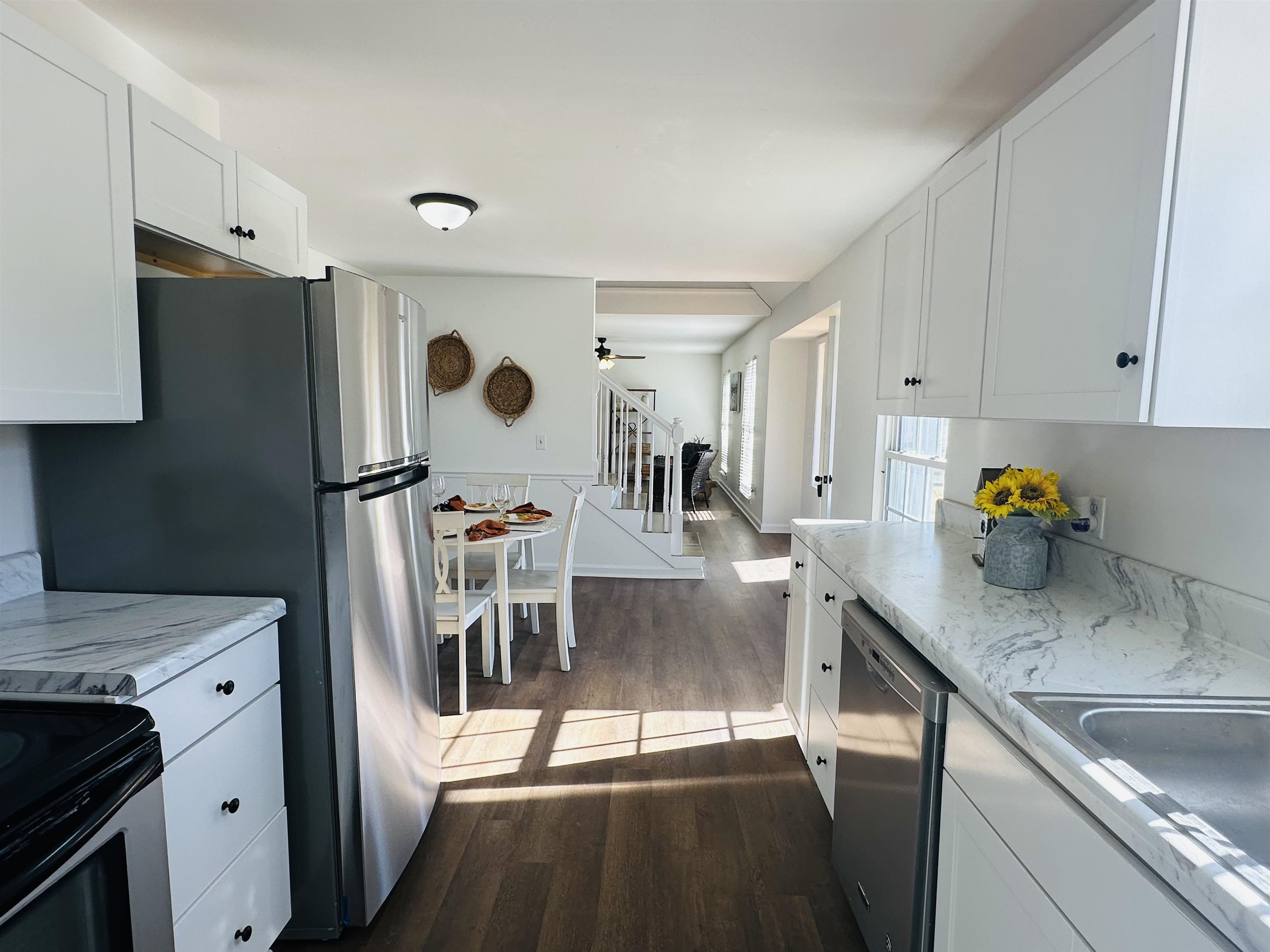 Kitchen featuring light stone countertops, dark hardwood / wood-style flooring, stainless steel appliances, ceiling fan, and white cabinets