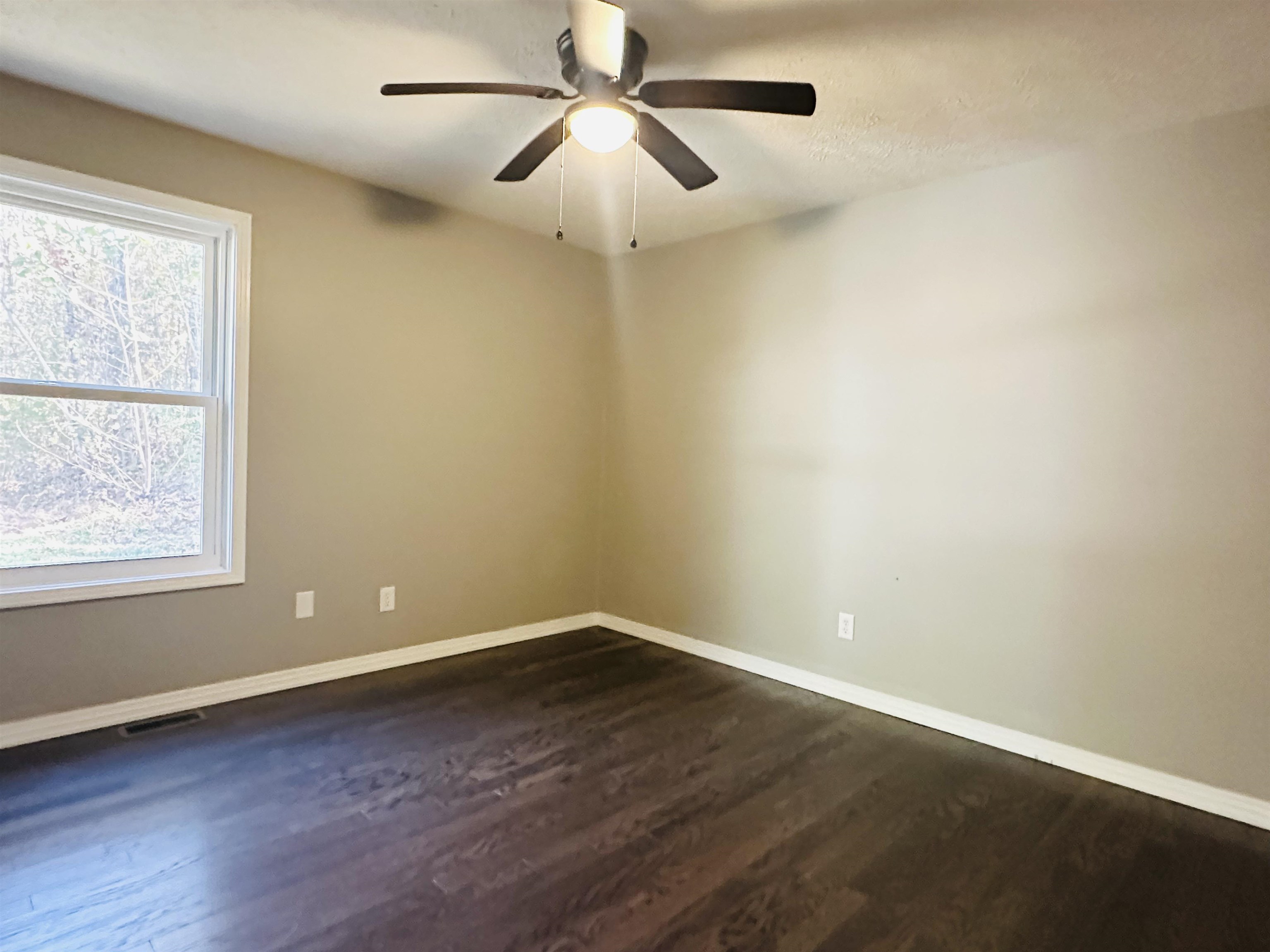 Spare room featuring ceiling fan and dark hardwood / wood-style flooring