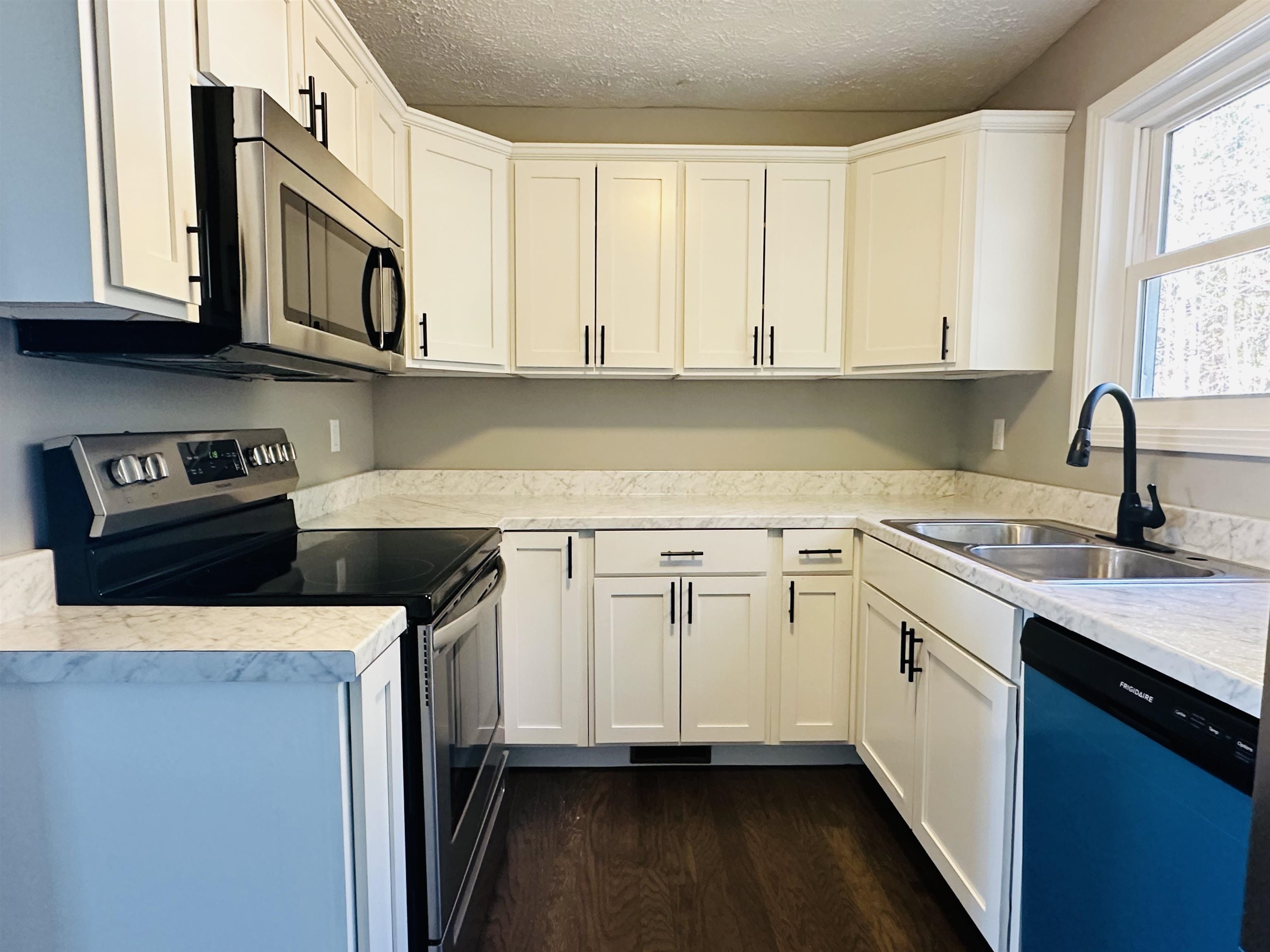 Kitchen with dark wood-type flooring, white cabinets, sink, a textured ceiling, and appliances with stainless steel finishes