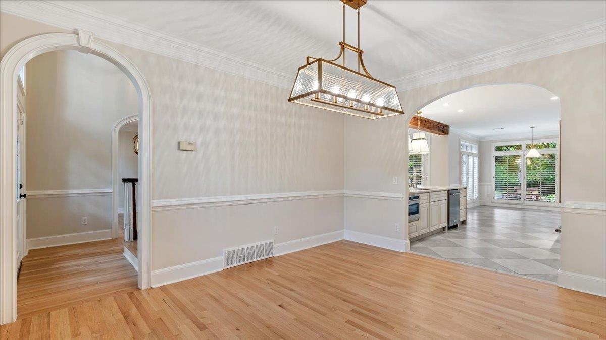 Unfurnished dining area with sink, ornamental molding, and light wood-type flooring