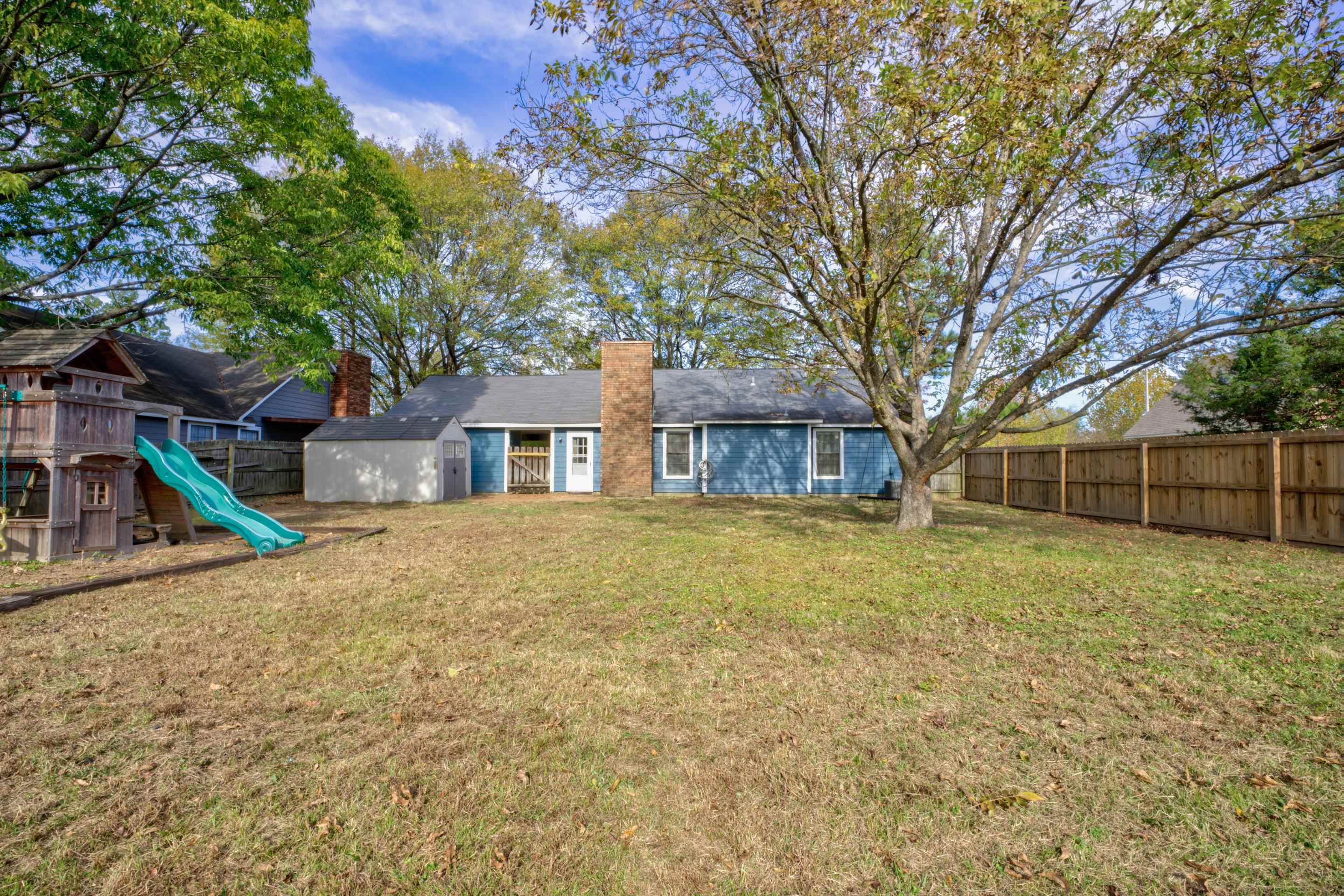 Rear view of property with a playground and a lawn