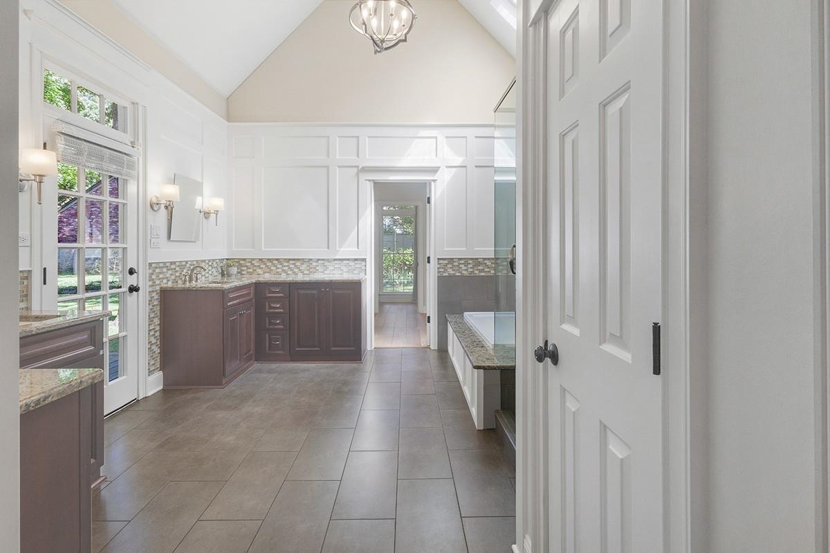 Bathroom with sink, tasteful backsplash, high vaulted ceiling, tile patterned floors, and a chandelier