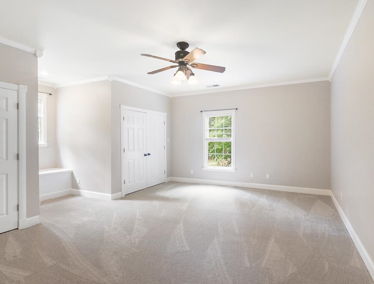 Unfurnished bedroom featuring ceiling fan, light colored carpet, and crown molding