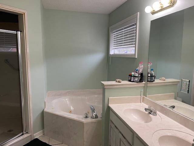 Bathroom with vanity, separate shower and tub, and a textured ceiling