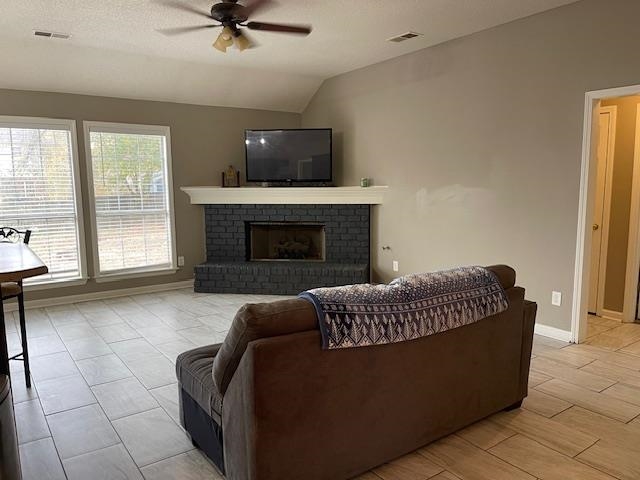 Living room featuring a fireplace, vaulted ceiling, and ceiling fan