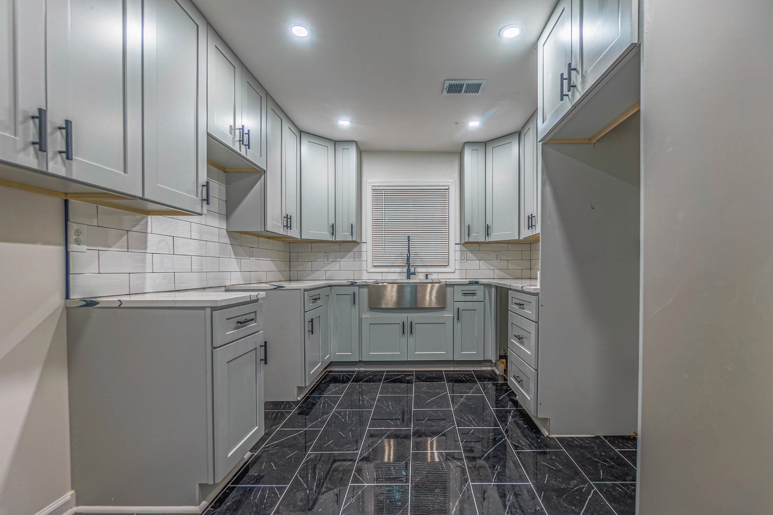 Kitchen with white cabinets, sink, and tasteful backsplash