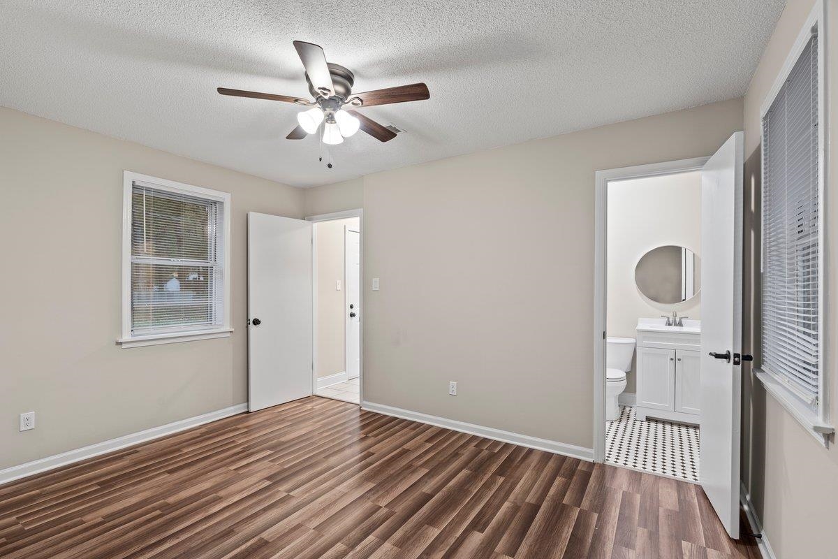 Unfurnished bedroom with dark hardwood / wood-style flooring, ensuite bath, a textured ceiling, ceiling fan, and sink