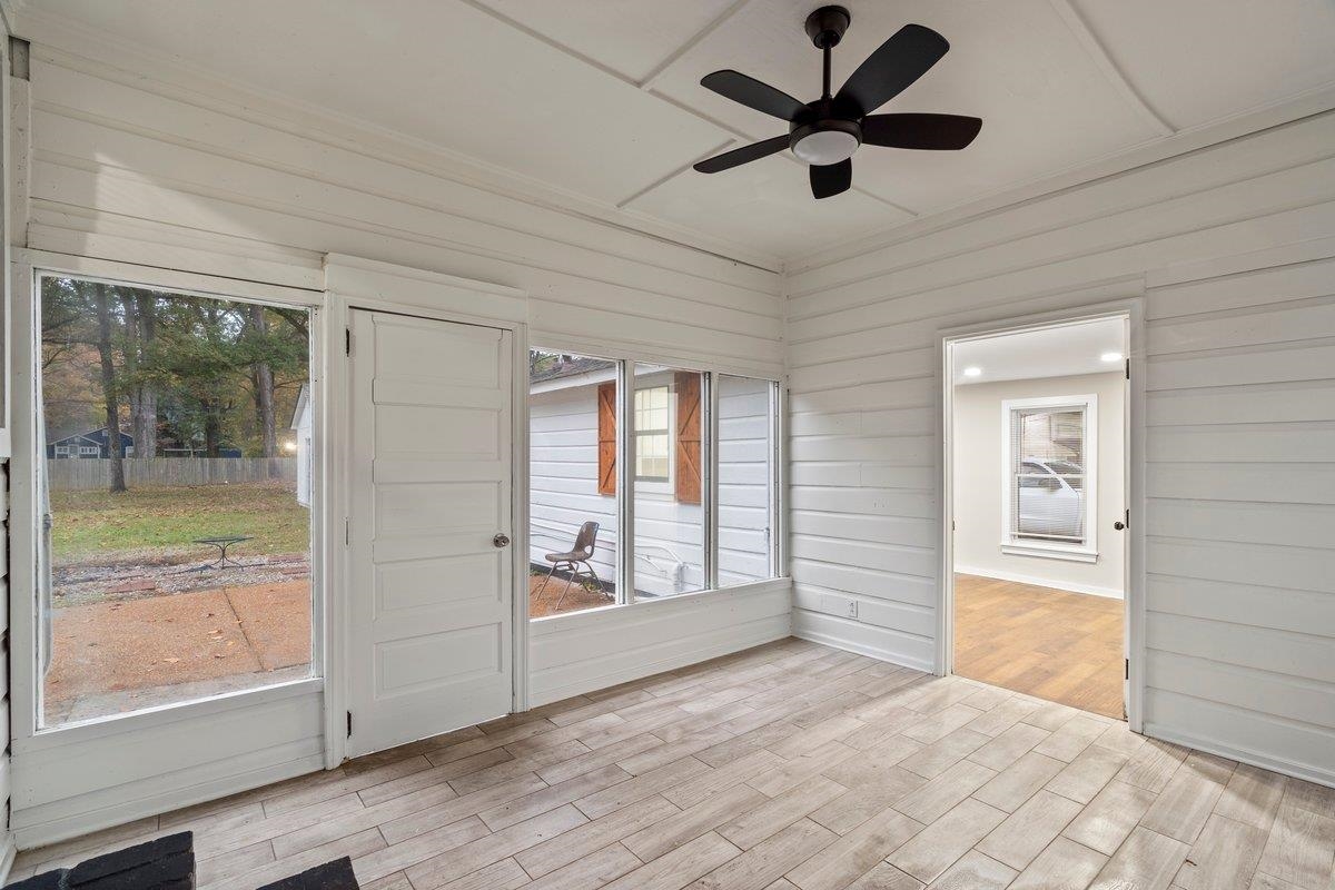 Unfurnished sunroom featuring a wealth of natural light and ceiling fan