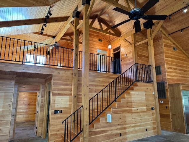 Staircase with wood walls, beamed ceiling, high vaulted ceiling, and wood ceiling