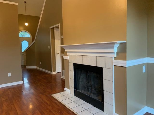 Unfurnished living room featuring light hardwood / wood-style floors, high vaulted ceiling, and a tiled fireplace