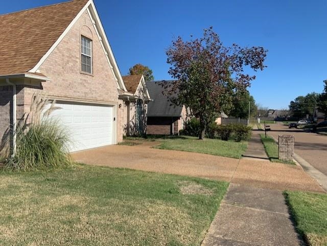 View of side of property with a lawn and a garage