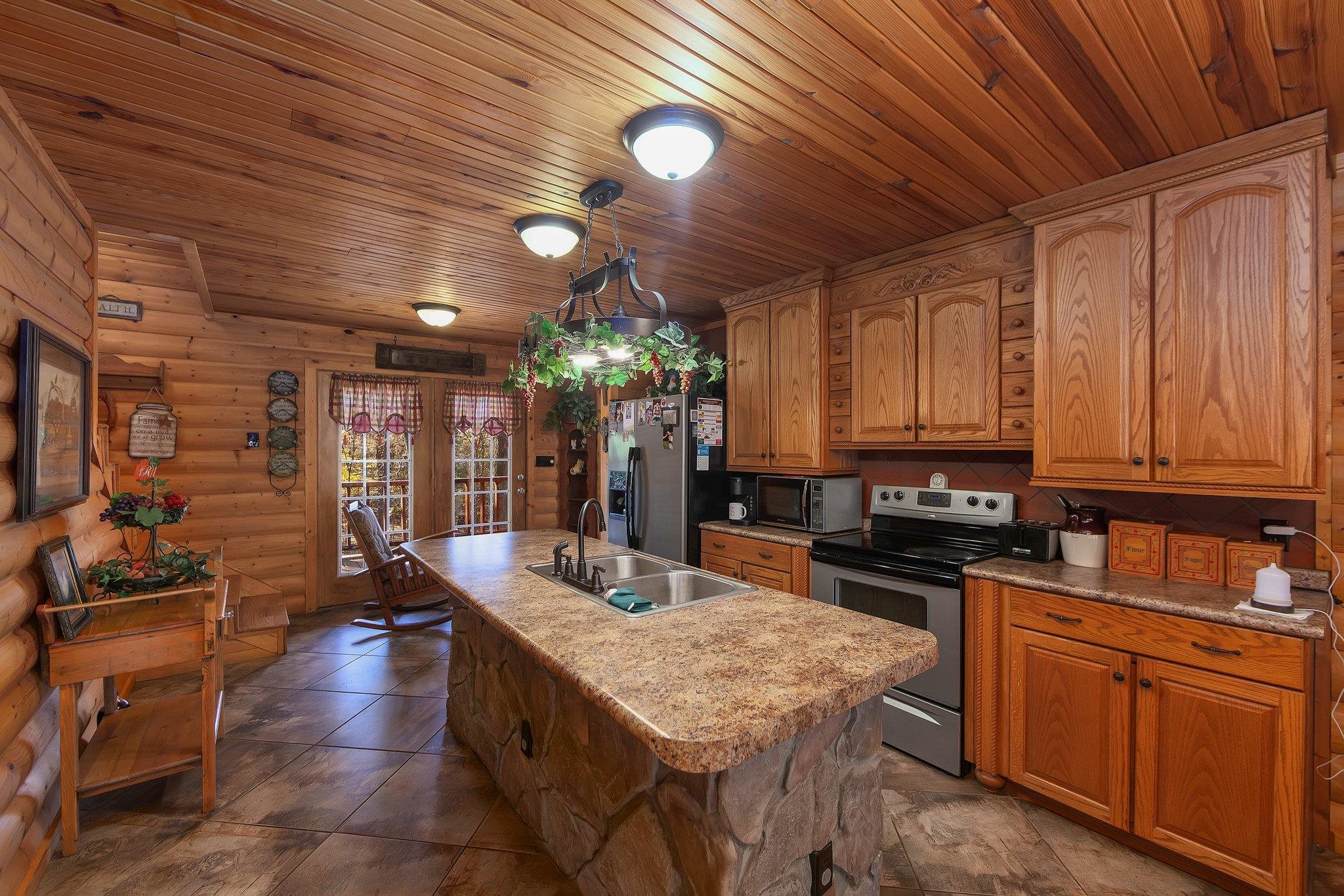 Kitchen featuring sink, an island with sink, decorative light fixtures, wood ceiling, and stainless steel appliances