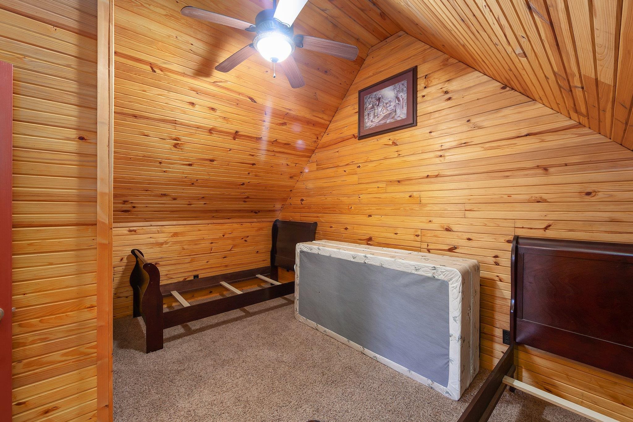 Bedroom with lofted ceiling, ceiling fan, wooden ceiling, and wood walls