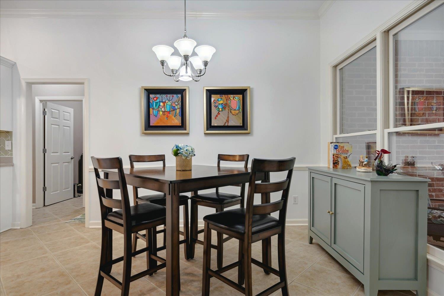 Dining space featuring crown molding, light tile patterned floors, and an inviting chandelier