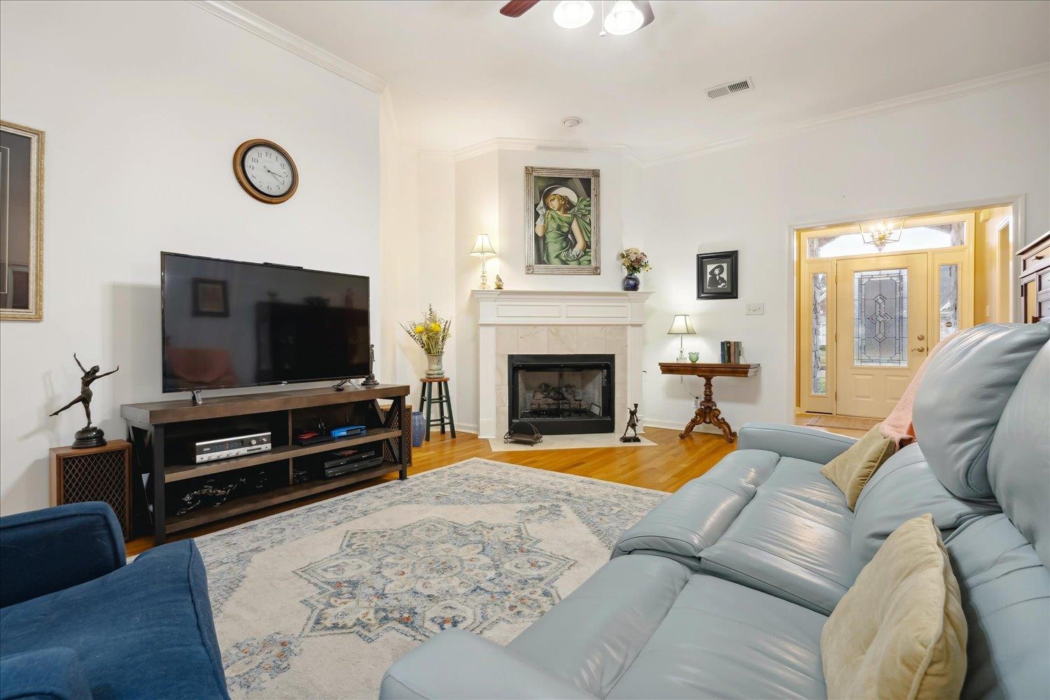 Great Room with a fireplace, wood-type flooring, ceiling fan, and Crown molding