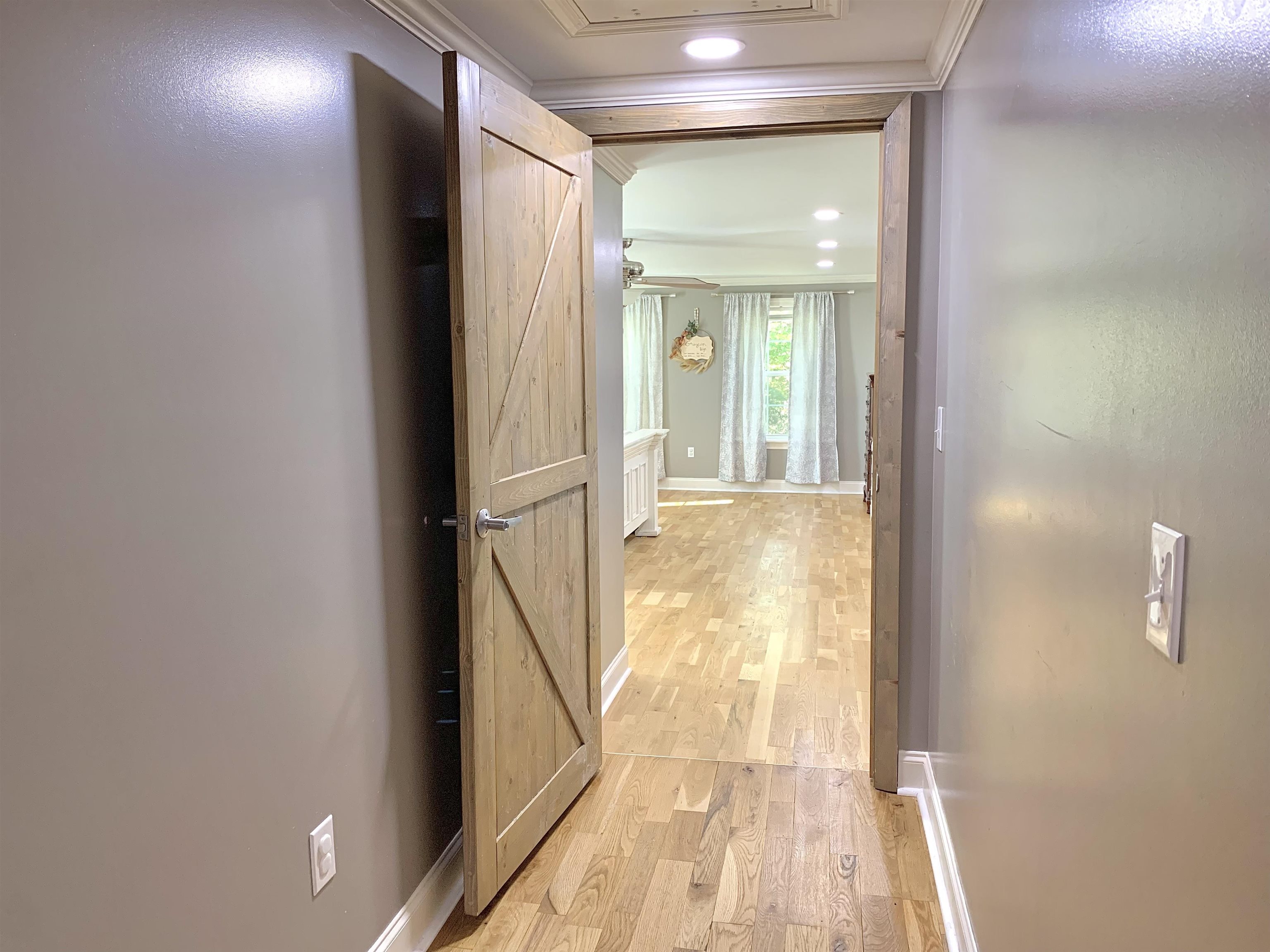 Hallway with light hardwood / wood-style flooring and ornamental molding