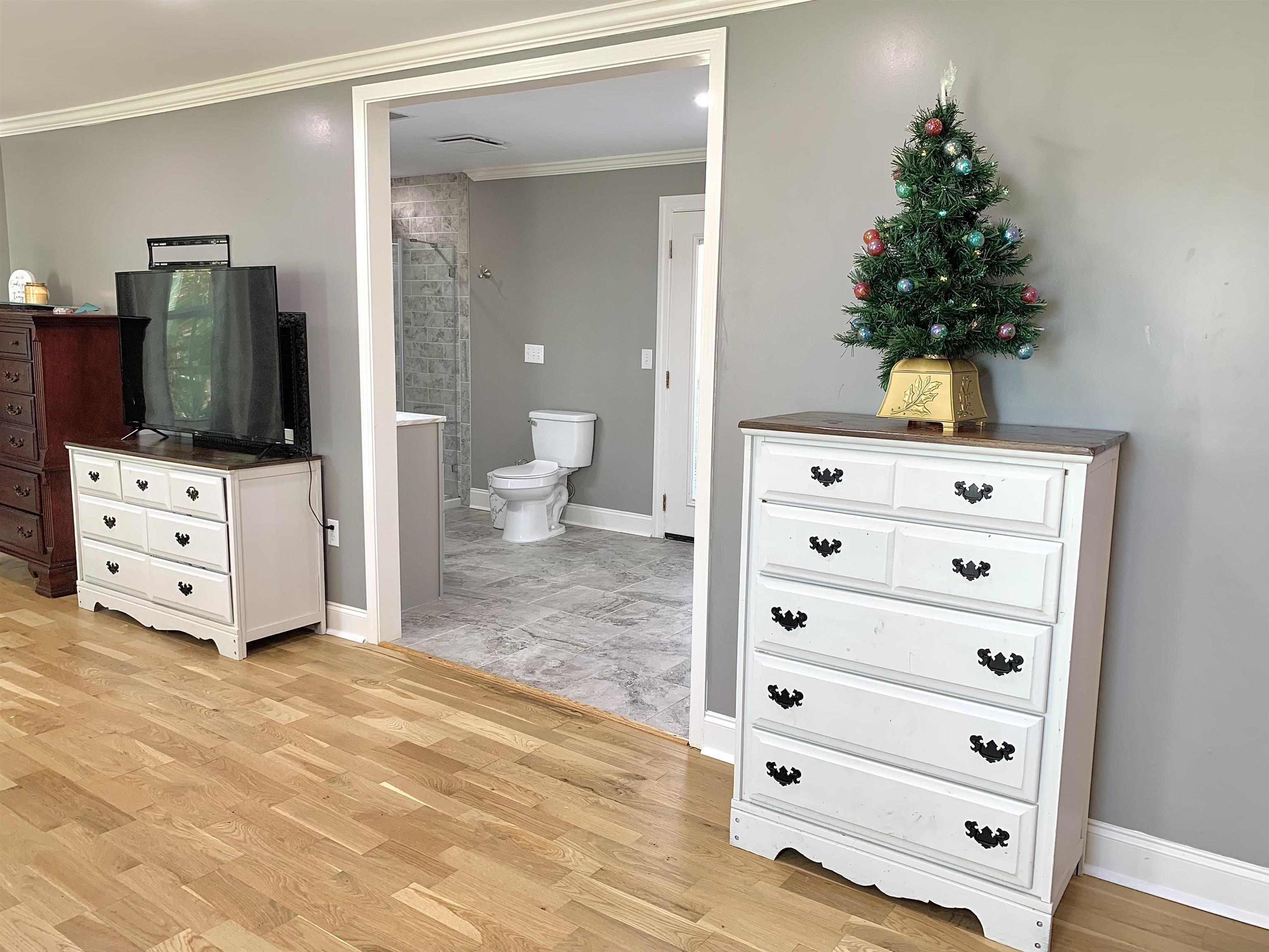 Bathroom featuring hardwood / wood-style floors, toilet, and ornamental molding