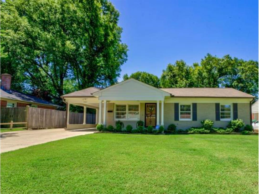 Ranch-style house featuring a carport, covered porch, and a front lawn